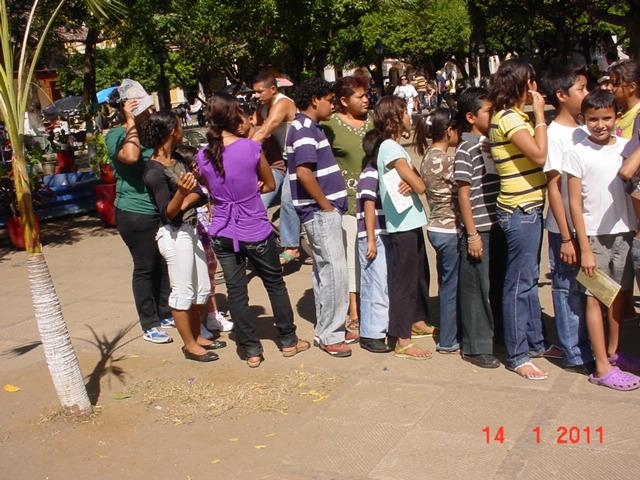 Ninos haciendo fila para recibir su mochila